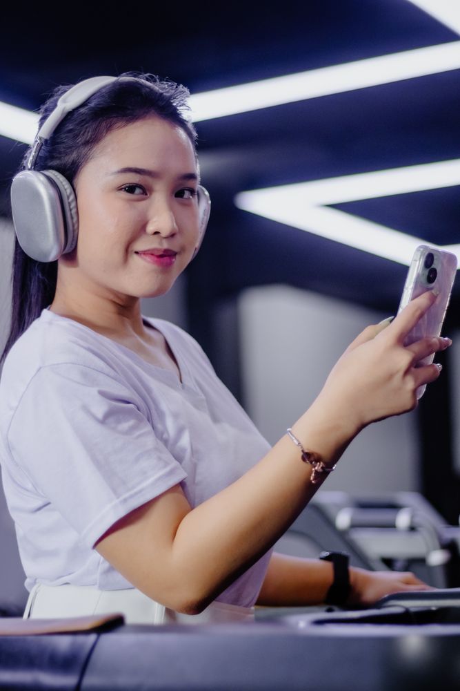 Young sporty woman enjoys music while working out on treadmill