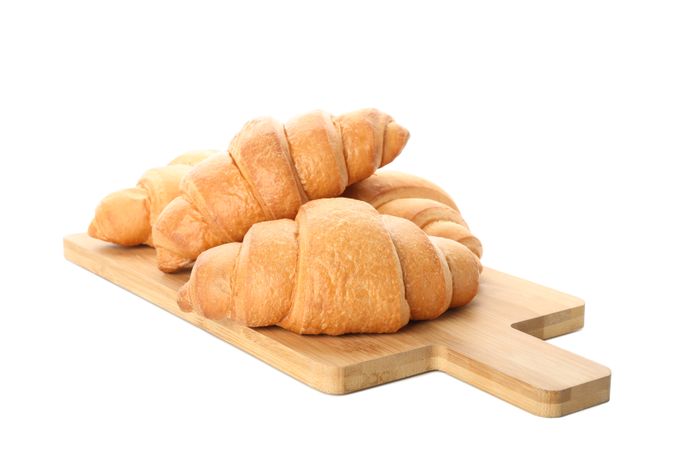 Cutting board with croissants isolated on plain background