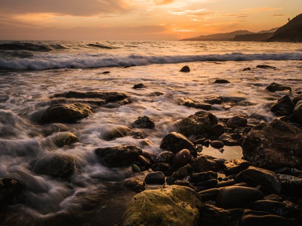Stony seashore and waves at beautiful sunset