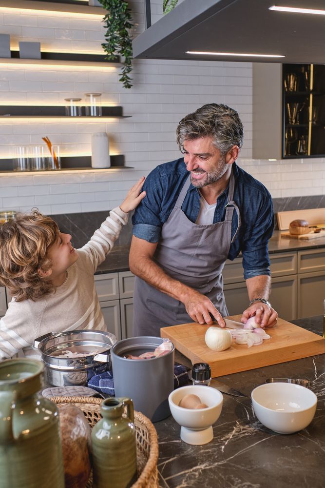 Positive father with son cooking in kitchen