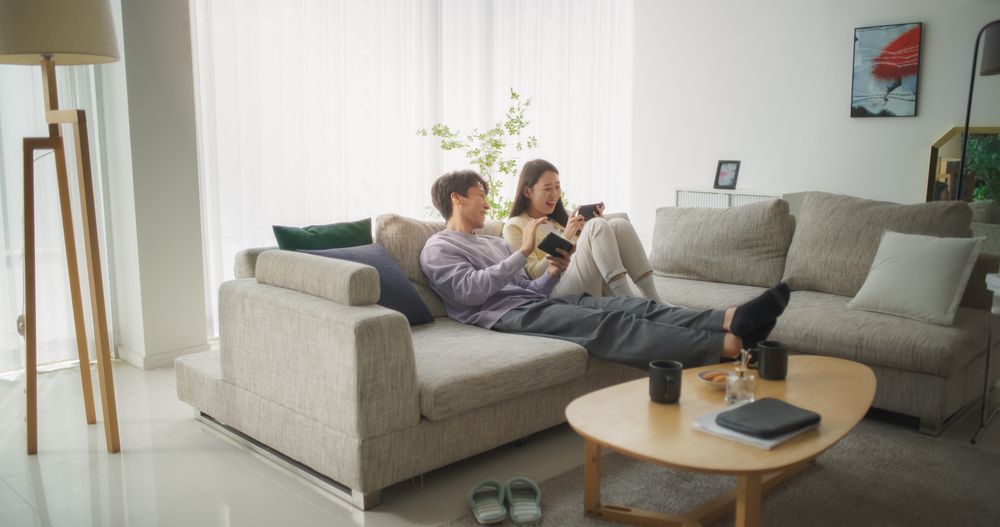 South Korean Couple Sitting on a Cozy Couch, Playing Funny Arcade Video Games Together