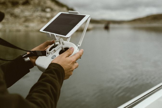 Person controlling device using tablet on stand in hands