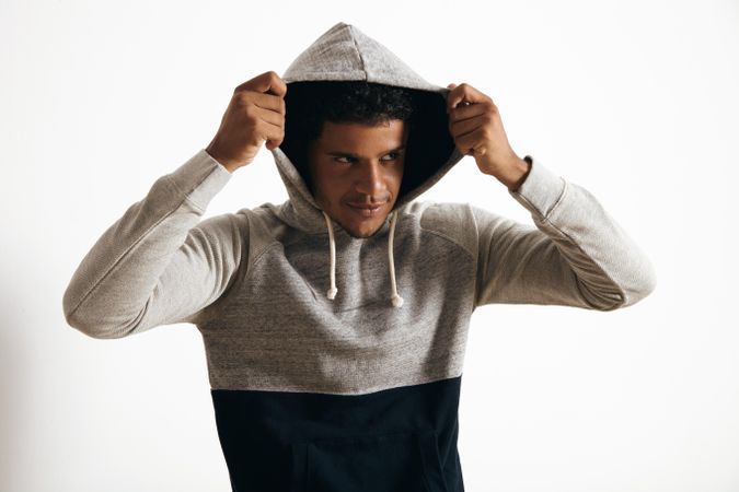 Smirking man putting up hood on sweater