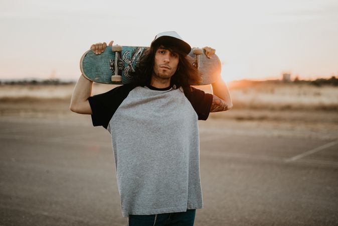 Cool confident man with skateboard looking at camera