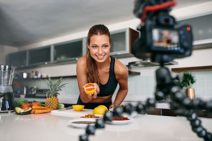 Lean woman showing a cut lemon facing the camera