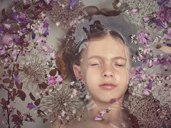 Boy lying underwater in bathtub with flowers