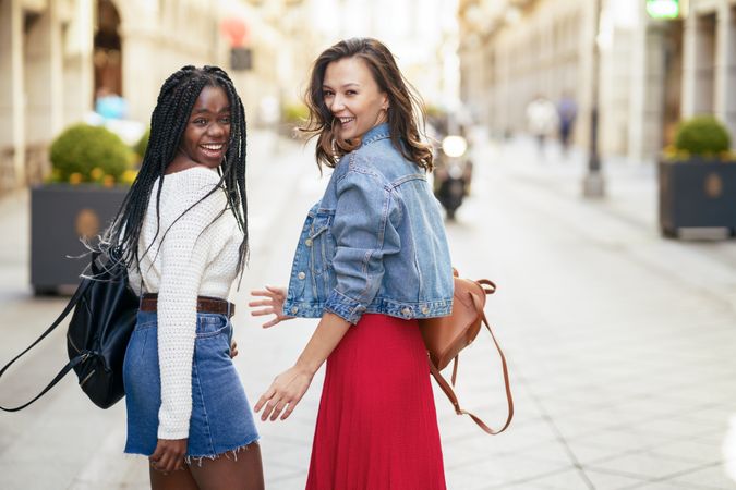 Female friends walking on an outdoor street while looking back