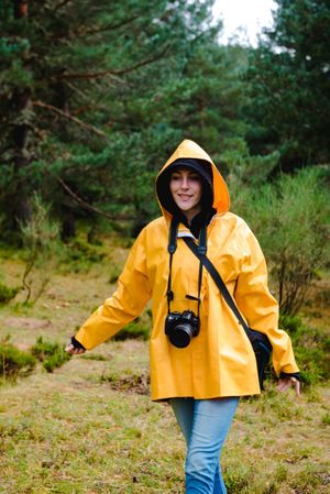 Person in hood and yellow raincoat walking i forest