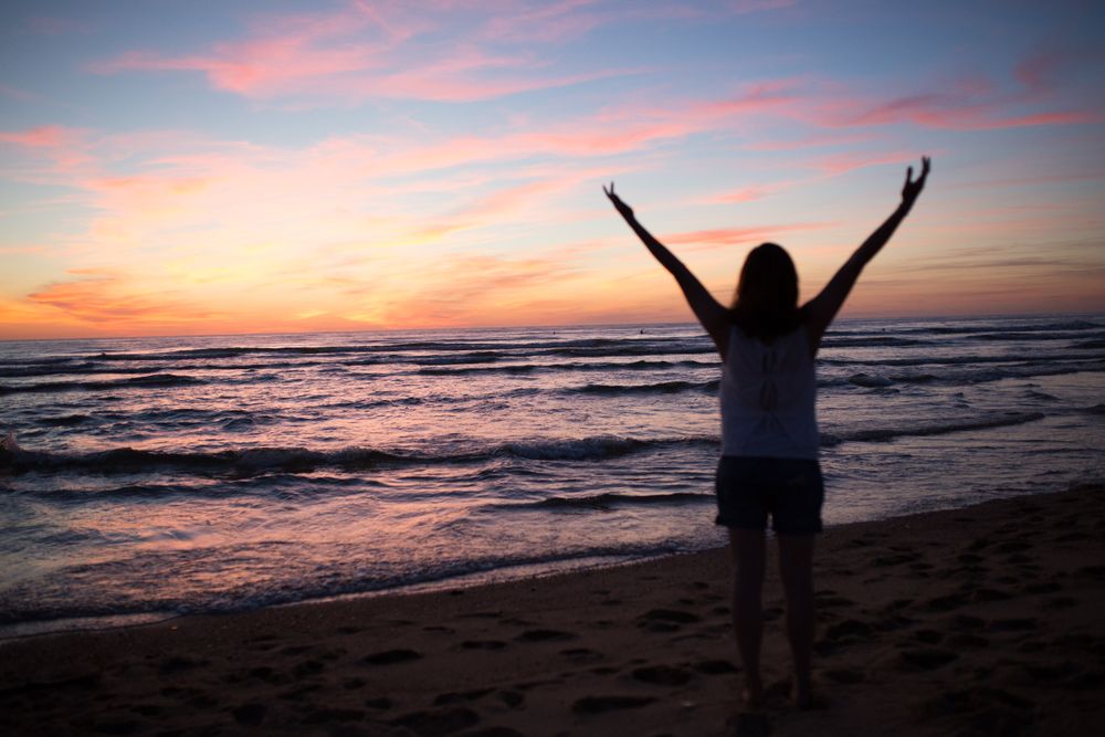 Female tourist posing on seaside at sunset