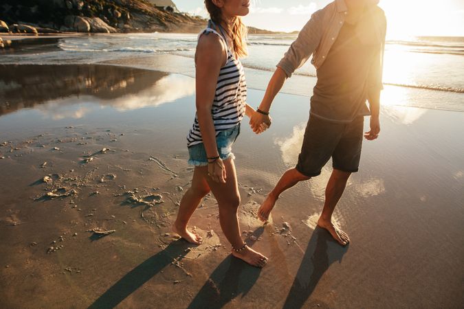 Young man and woman walking on the beach together