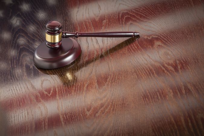 Wooden Gavel Resting on Flag Reflecting Table
