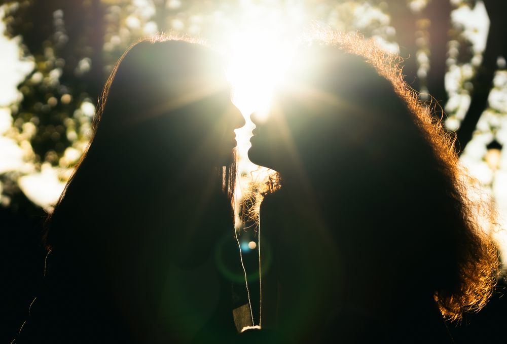 silhouette of two women kissing in the sunlight