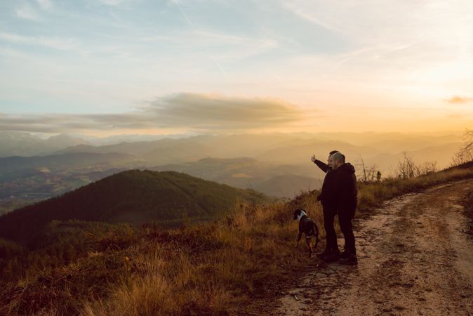 Men hugging near dog on road on hill