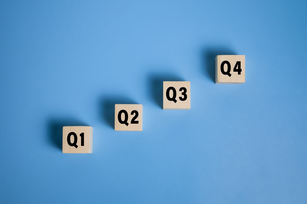 wooden cubes with q1, q2, q3, q4 symbol isolated on blue background. concept of quarterly report annual