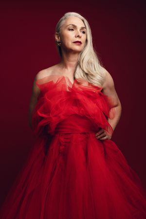 Portrait of mature woman wearing red ball gown looking down