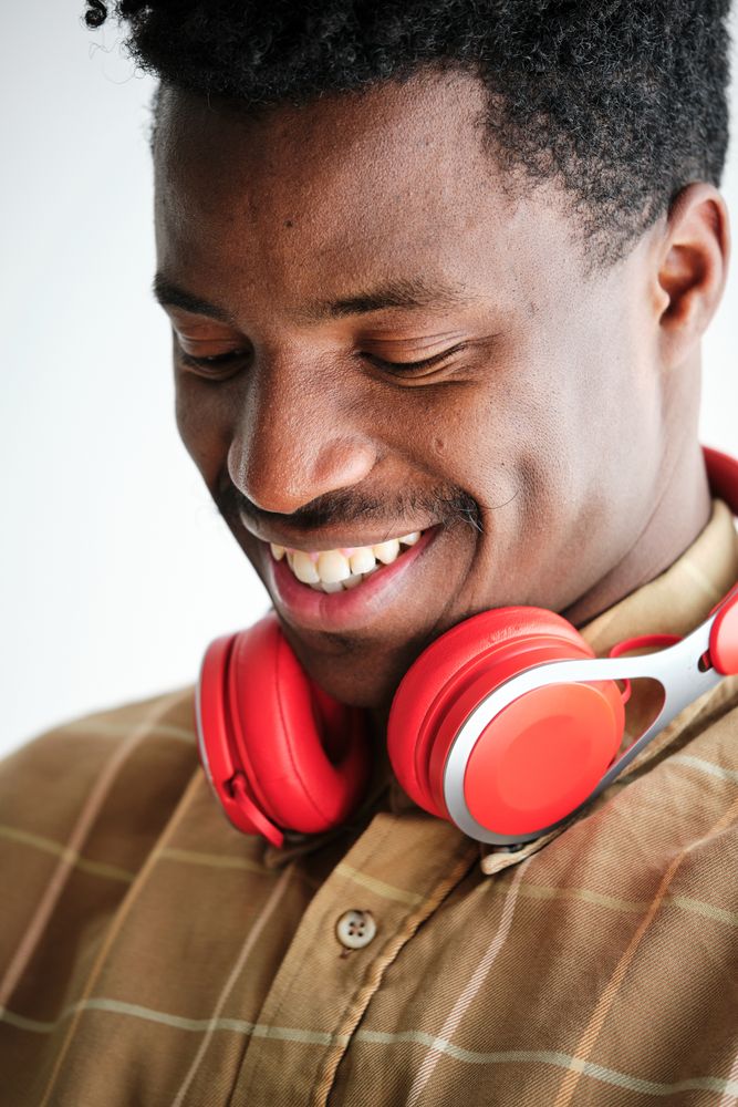 Cheerful Black man with headphones on white background