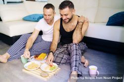 Two men eating breakfast on ground in living room 42zvg4