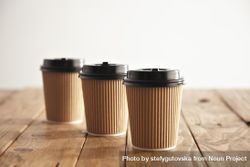 Three to go coffee cups on wooden table 42dOq0