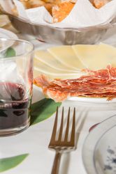 Typical spanish tapa with slices of serrano ham and manchego cheese, accompanied with a glass of Rioja red wine