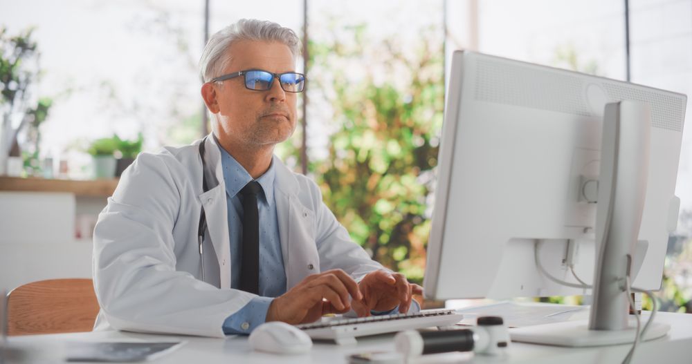 Healthcare Doctor Using Desktop Computer for Day-to-Day Hospital Operations.