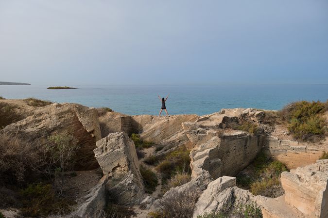 Unrecognizable female athlete exercising on cliff