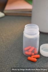 Red medical pills in container on counter 4ZeOAO
