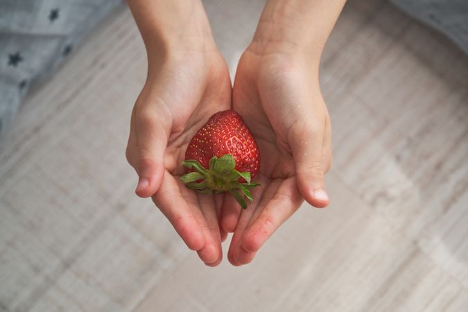 Faceless person with fresh red strawberry in cupped hands