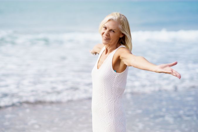 Side view of older woman opening her arms on a beautiful beach