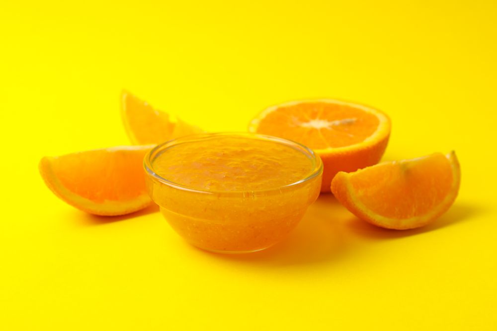 Delicious orange jam on yellow background, close up