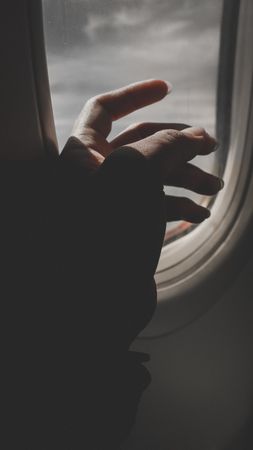 Cropped image of hand beside plane window