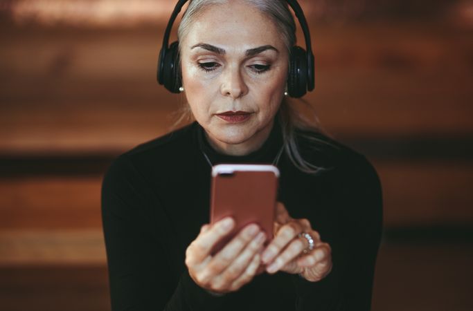 Close up of older woman  listening on phone with headphones