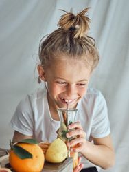 Happy little kid drinking fresh lemonade from glass