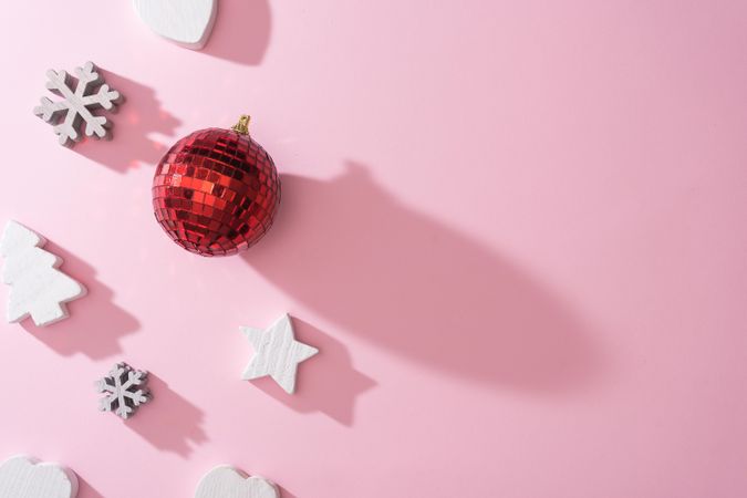 Wooden snowflakes hearts and decorations with red disco ball bauble on pink back with shadows
