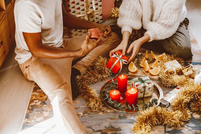 Couple sitting on the ground unwrapping Christmas gifts for each other