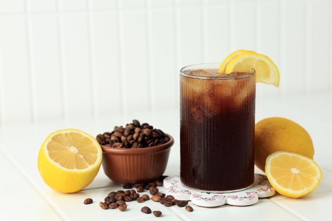 Coffee with Tonic in a Tall Glass with Ice and Lemon on Table Background.