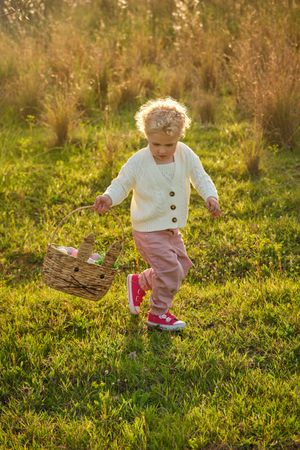 Content girl with basket strolling on lush lawn