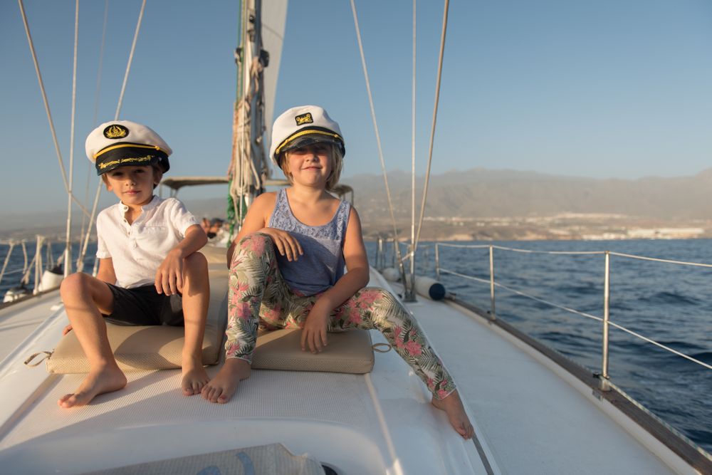 Smiling children sitting on deck of yacht in sea