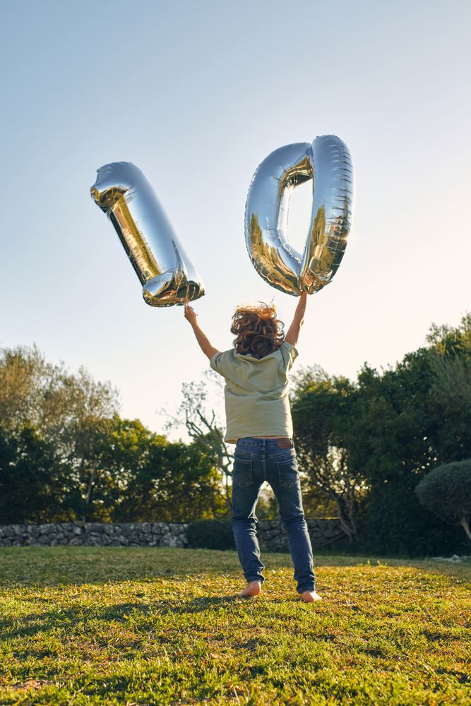 Unrecognizable boy with number balloons during birthday on meado