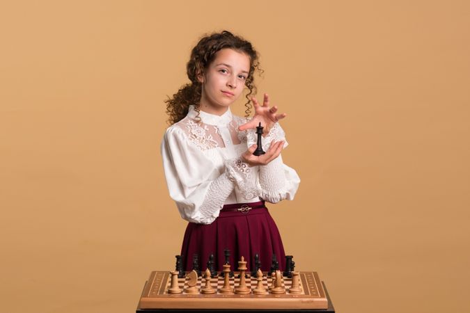 Young girl holding chess piece while posing gracefully.