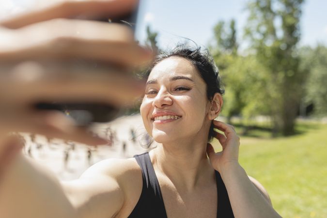 A young woman, wearing braces and invisible clear aligners, takes photos selfies with her mobile phone, in the park doing sports
