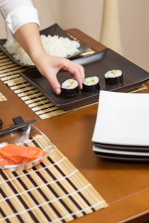 Chef placing freshly made sushi rolls on plate