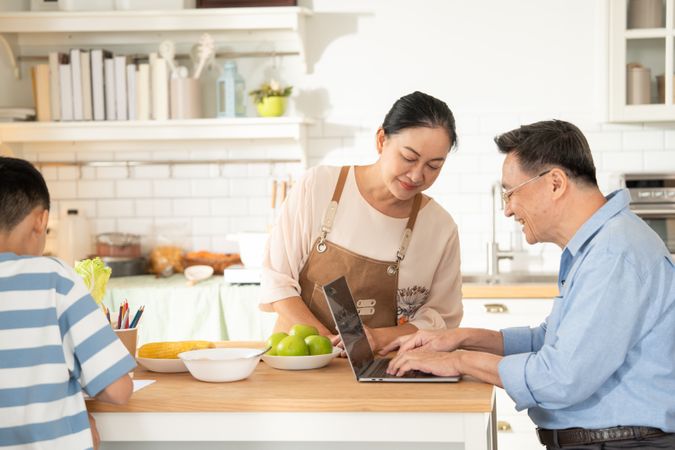 Asian grandmother watching and talking with grandson while doing homework