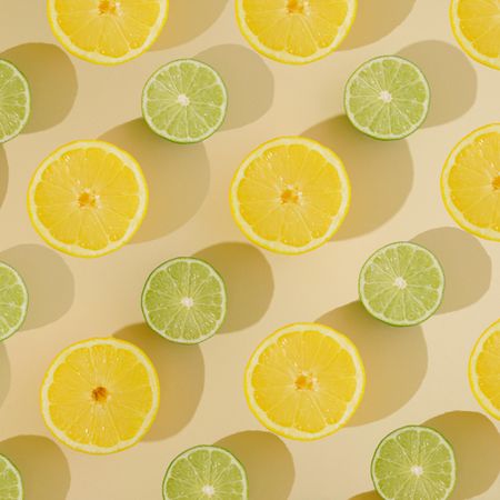Fresh summer fruit with lemon and lime pattern on sandy background