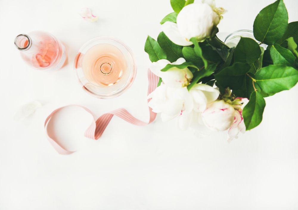 Top view of pink rose wine, and bottle with flowers and ribbon, horizontal composition, copy space