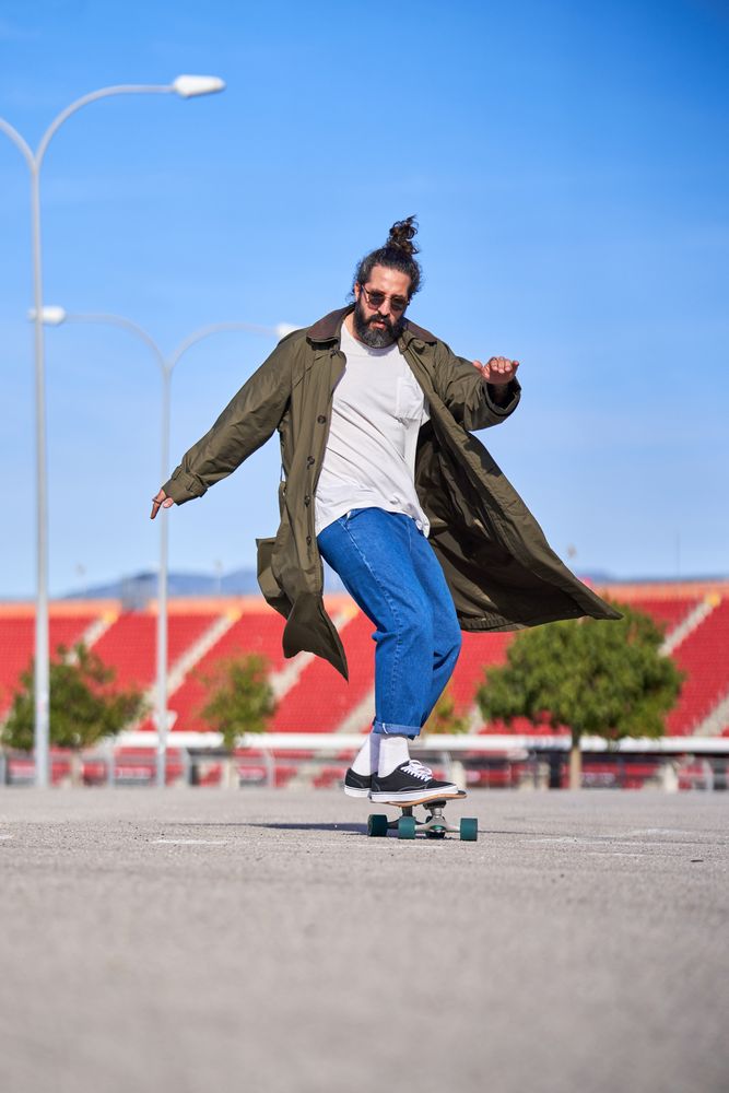 Stylish hipster man riding longboard in skate park