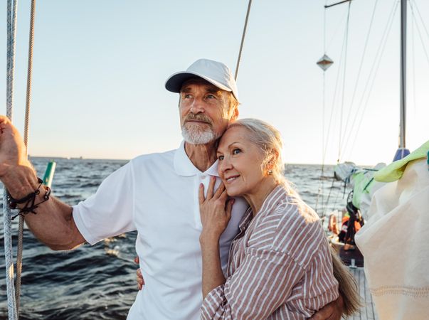 Older loving couple standing together on sailboat