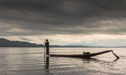 Shan, Myanmar - June, 25 2012: Anonymous fisherman standing on boat