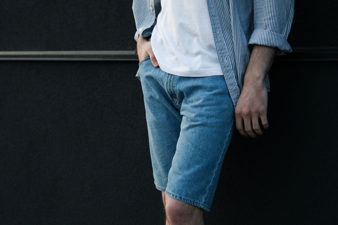 Young man stands against wall. Space for text