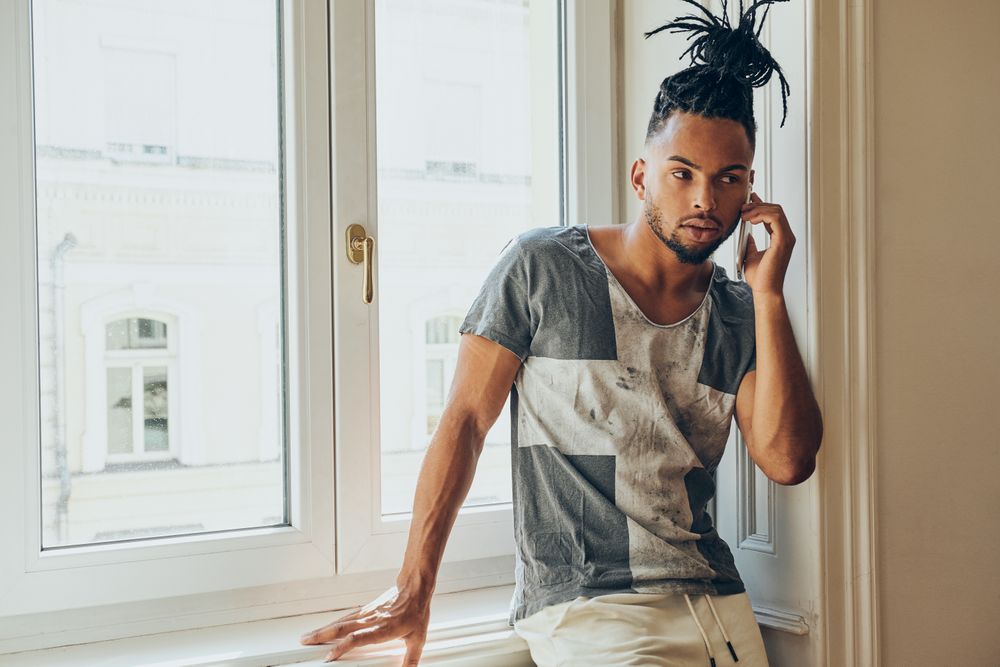 Black braided male using smartphone