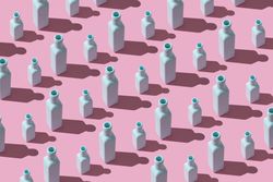 Rows of painted glass bottles on pink background